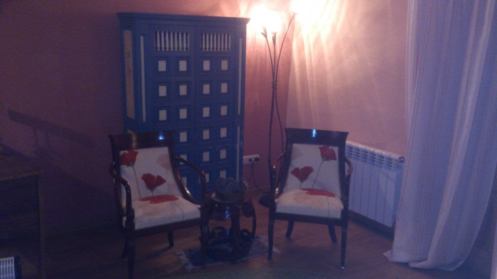 Una habitación con dos sillones, una mesita y un radiador.