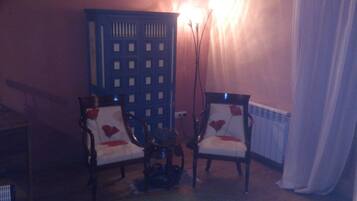 Una habitación con dos sillones, una mesita y un radiador.