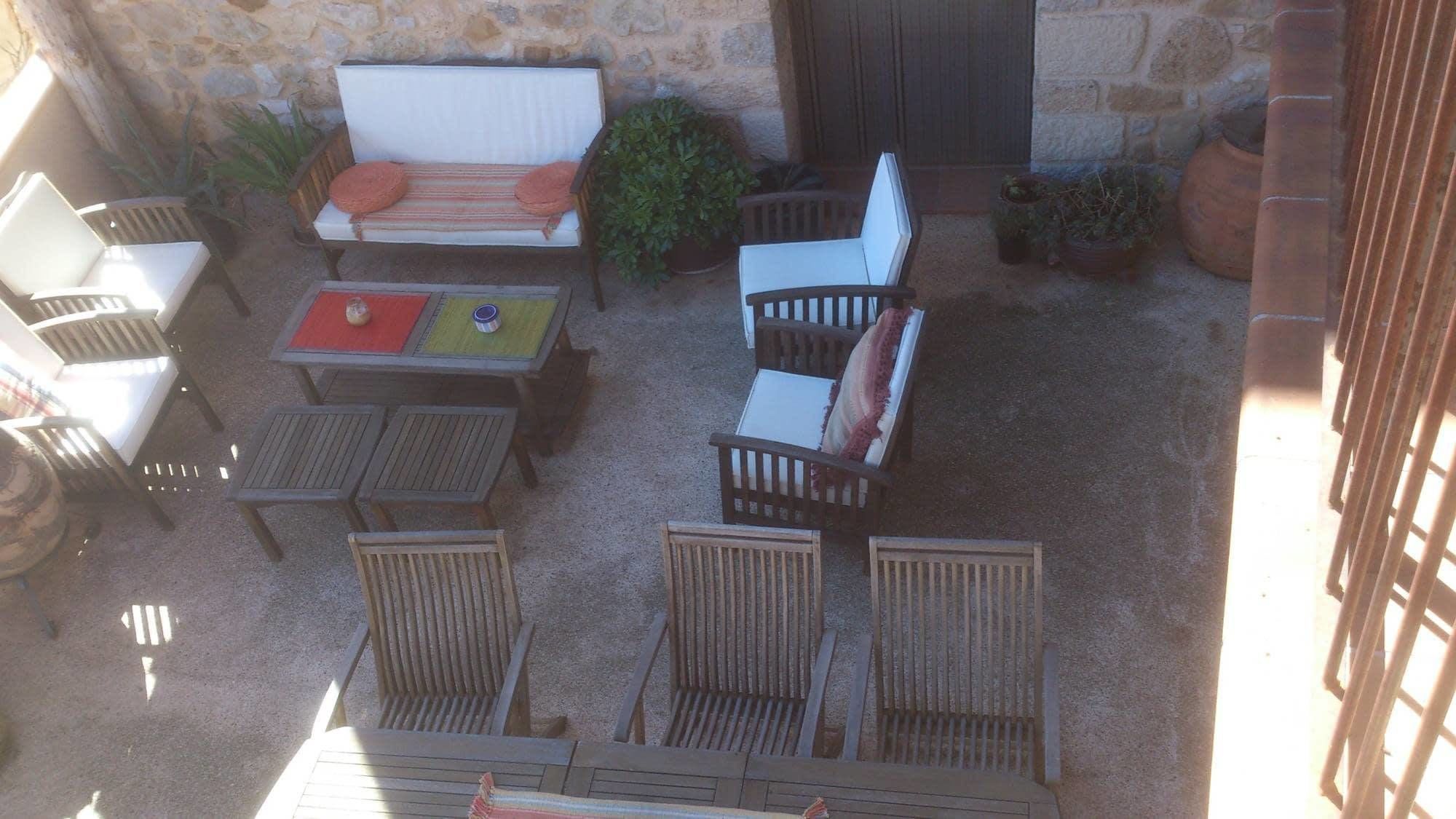 An outdoor patio with wooden furniture, including a sofa, chairs, and tables.
