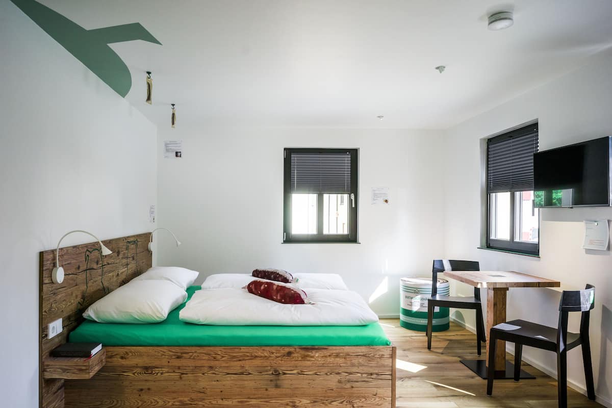 Ein kleines, modernes Zimmer mit einem hölzernen Bett, einem Schreibtisch und einem Stuhl.