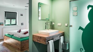 Une salle de bain moderne avec un meuble-lavabo en bois, un grand miroir et un mur vert.