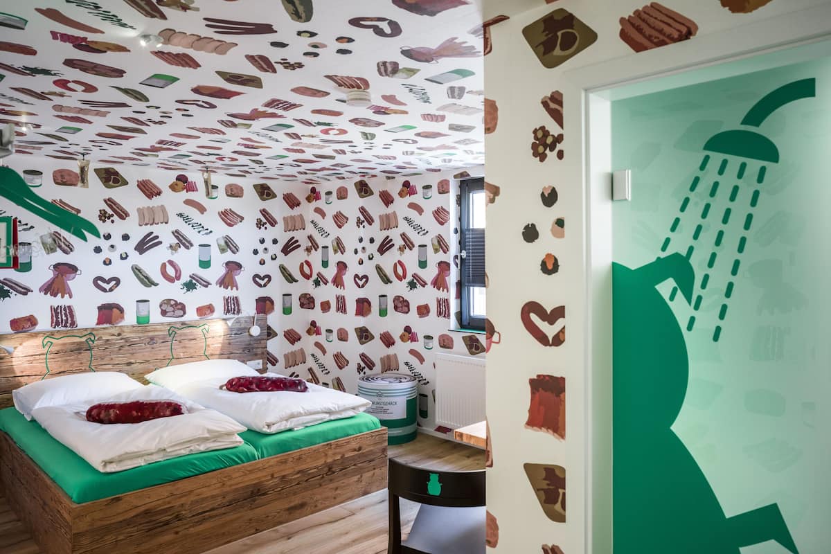 Ein Schlafzimmer mit einem hölzernen Bett, grüner Bettwäsche und einer Wand mit Illustrationen von Lebensmitteln.