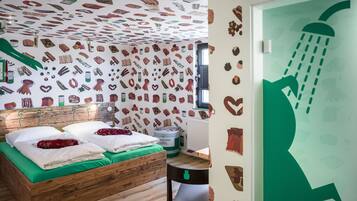 A bedroom with a wooden bed, green bedding, and a wall decorated with food illustrations.