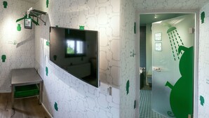 Une salle de bain avec un robinet vert, un miroir et un espace douche.