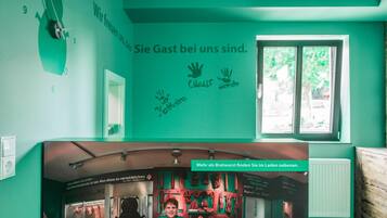 Een kamer met teal muren, een raam en een wandklok. Er is een bord met handafdrukken en tekst.