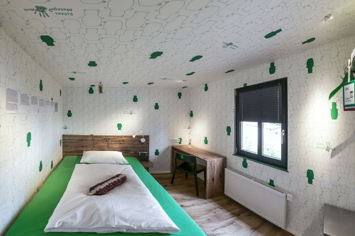 Ein Zimmer mit einem Bett, einem Holztisch und einem Fenster.
