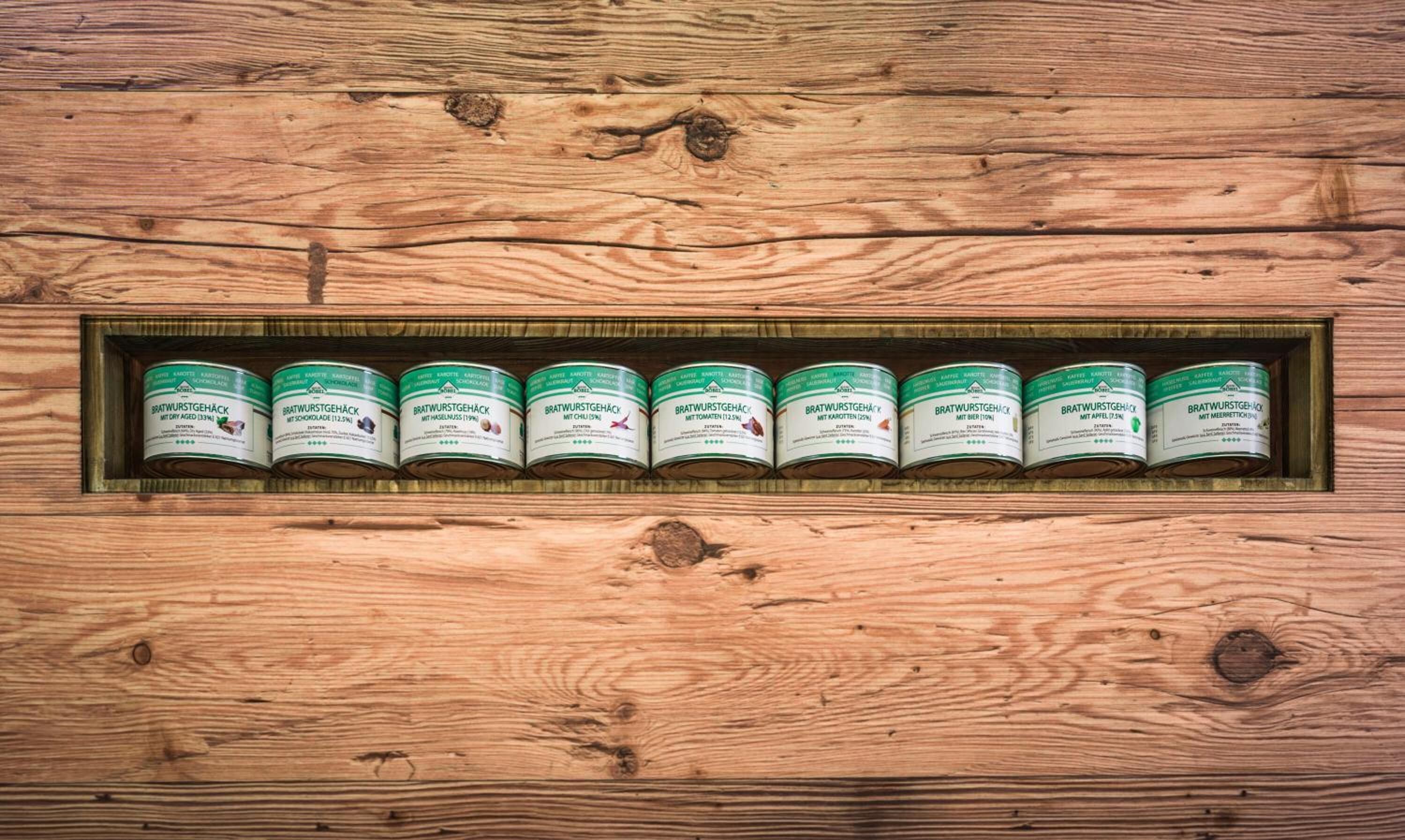Una estantería de madera con varias latas de Bratwurstgehack.