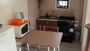 A compact kitchen with a microwave, stove, sink, and a small window. - Departamentos Arlenne II (Valdivia)