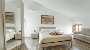 A bedroom with a bed, bedside tables, a mirror, a sofa, and two paintings on the wall. - B&B Locanda Cistercense (Viterbo)