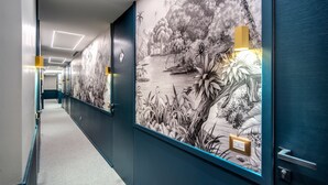 A hallway with a mural of a natural landscape, a light fixture, and a door with a handle. - Victor Boutique Hotel (Milan)