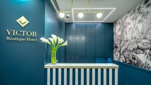 A reception desk with a blue wall and a tropical mural. - Victor Boutique Hotel (Milan)