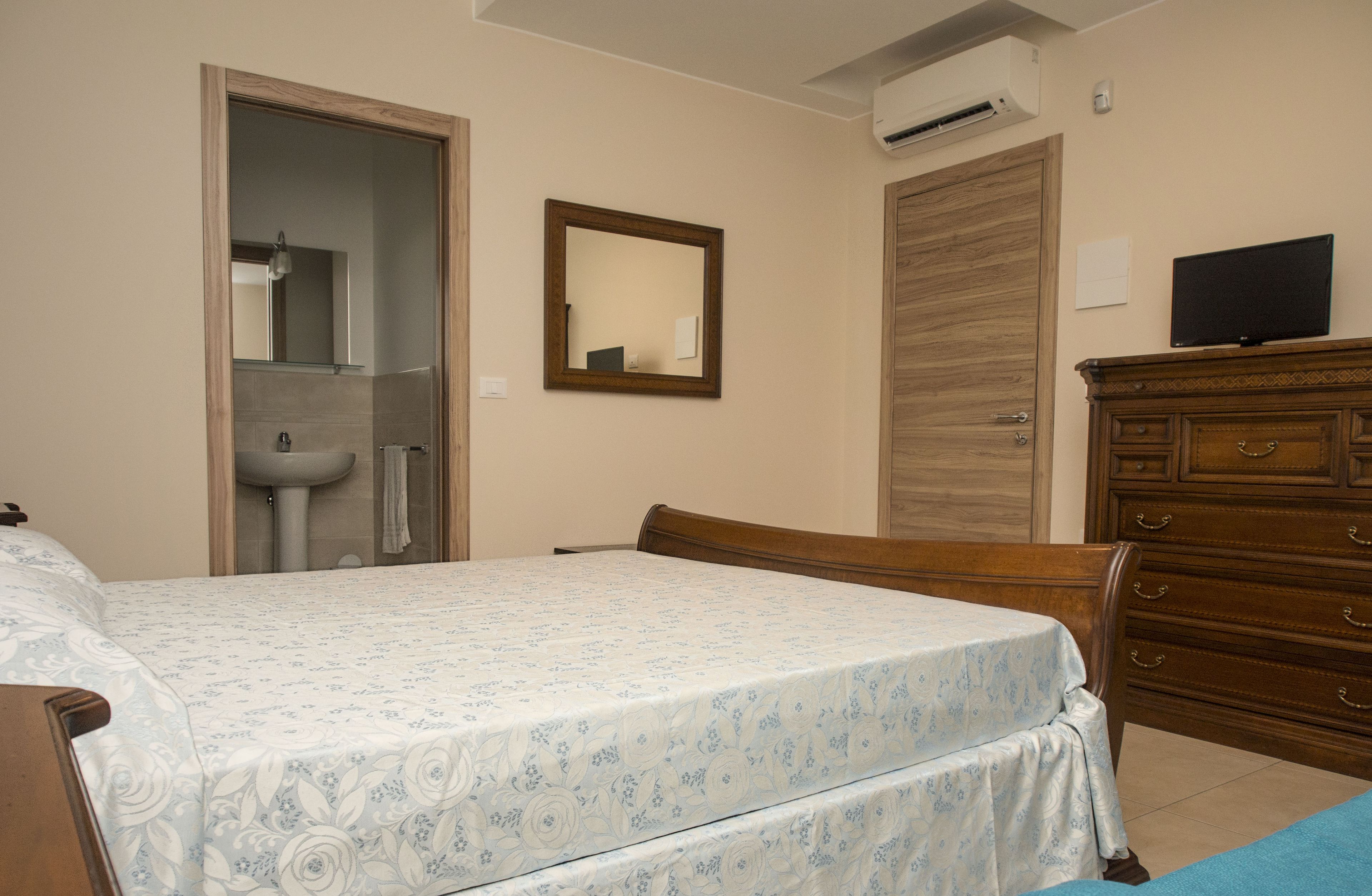 Un dormitorio con cama, cómoda, espejo y televisor.