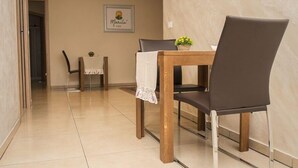 A dining area with a wooden table and two chairs, a small table with a plant, and a wall-mounted picture. - Marilu B&B (Matino)