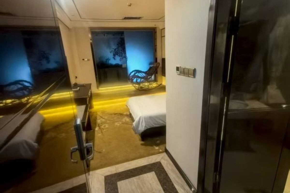 A hotel room with a bed, a chair, and a glass door.