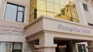 A hotel with a modern facade, featuring a large glass section and a sign that reads "Shanghai La Hotel". - Xinzheng Shangri-la Holiday Hot Spring Hotel (Zhengzhou)