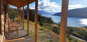 Eine Holzterrasse mit Stühlen mit Blick auf einen See und Berge.