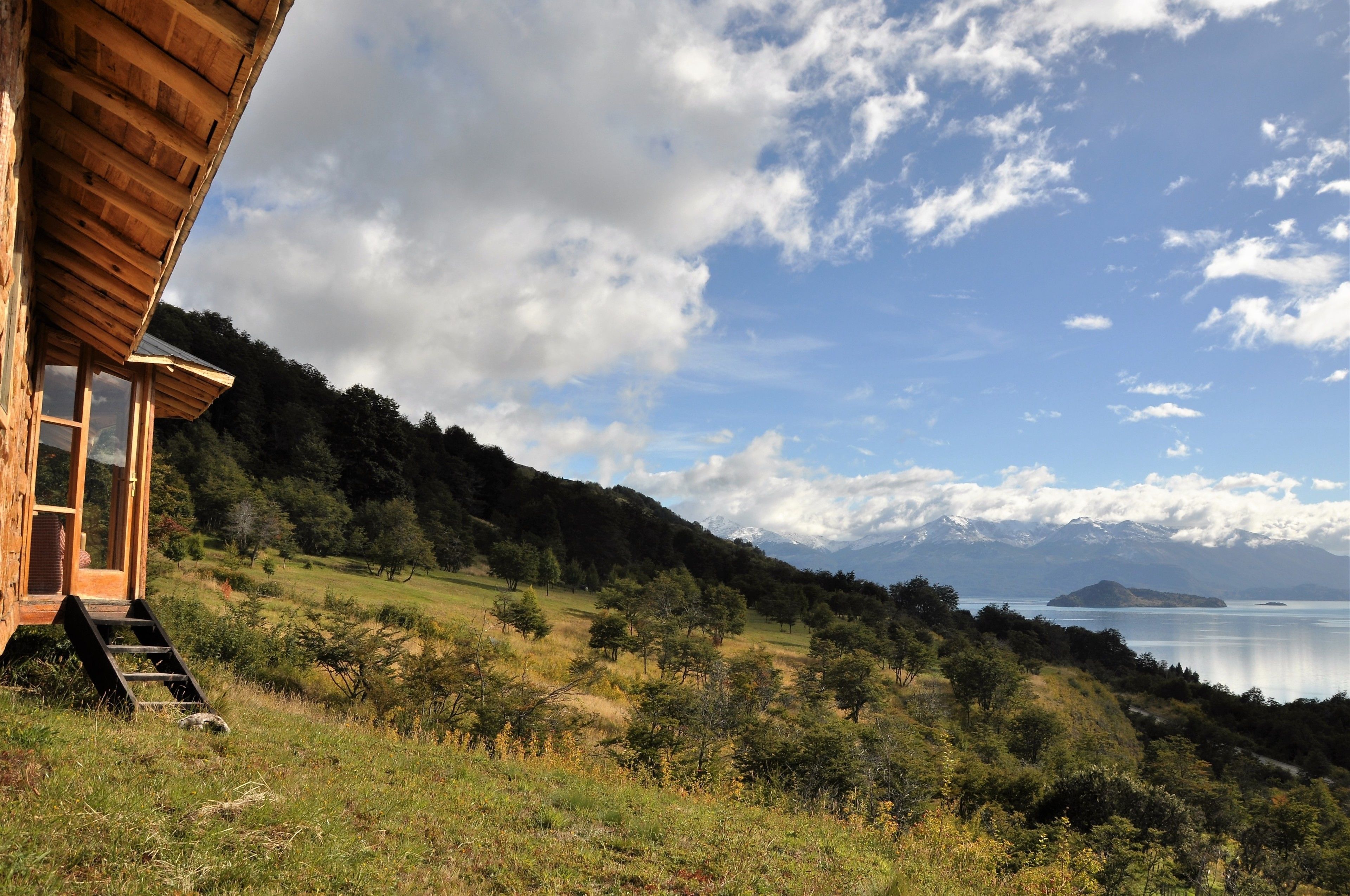 A wooden cabin with a view of a lake and mountains.