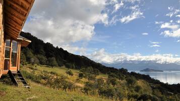 Uma cabana de madeira com vista para um lago e montanhas.