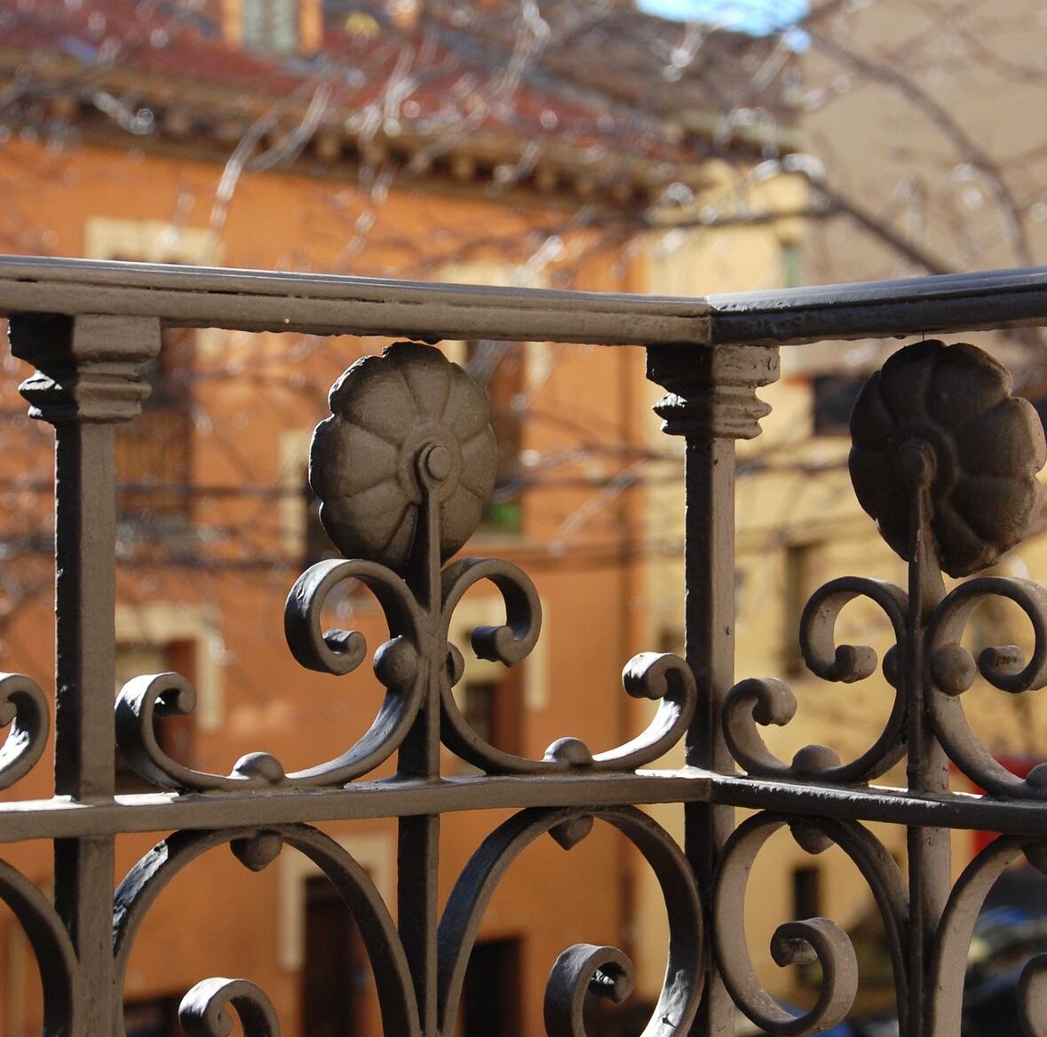 A wrought iron balcony railing with ornate floral designs.