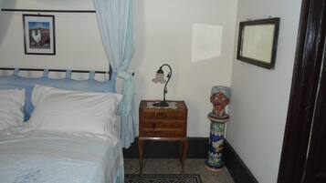A bedroom with a bed, a nightstand, a decorative vase, and a framed picture on the wall.