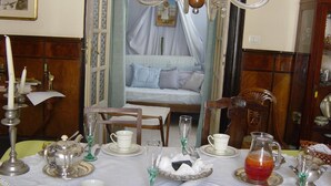 A dining table set with white plates, cups, and silverware, a pitcher of red beverage, and a vase with flowers. - Rosella Bianchi (Palermo)