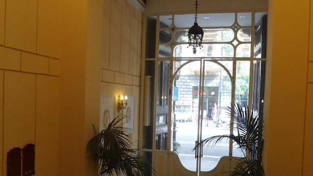 A lobby with a checkered floor, a large glass door, and two potted plants. - Rosella Bianchi (Palermo)