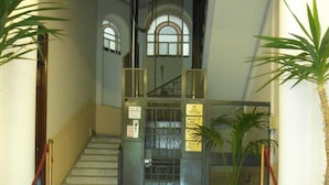 A marble staircase leading to a hotel entrance with a metal gate, potted plants, and a red rope barrier. - Rosella Bianchi (Palermo)