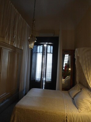 A bedroom with a bed, a hanging light fixture, and a window with curtains. - Rosella Bianchi (Palermo)