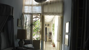 A cozy living room with a sofa, a lamp, and a view of a garden through a doorway. - Rosella Bianchi (Palermo)