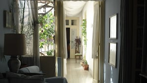 A room with a bed, a lamp, and a potted plant. There is a window with curtains and a view of greenery outside. - Rosella Bianchi (Palermo)