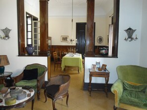 A traditional room with a dining area, a green armchair, a wooden chair, and a table with a green tablecloth. - Rosella Bianchi (Palermo)