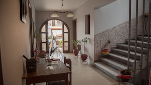 Un comedor espacioso con una mesa y sillas de madera, plantas en macetas y una escalera que conduce a un nivel superior.