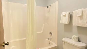 A bathroom with a bathtub, toilet, and a shower curtain.