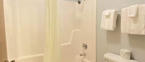 Un baño con bañera, inodoro y cortina de ducha.