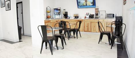 A modern kitchen with a dining area, equipped with a coffee machine, microwave, and refrigerator.