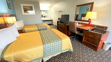 Habitació d'hotel amb dos llits, un escriptori, una cadira, un televisor, un mirall i una làmpada.