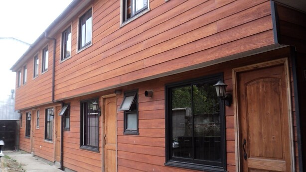 Un edificio de madera de dos pisos con varias ventanas y una puerta de madera grande.