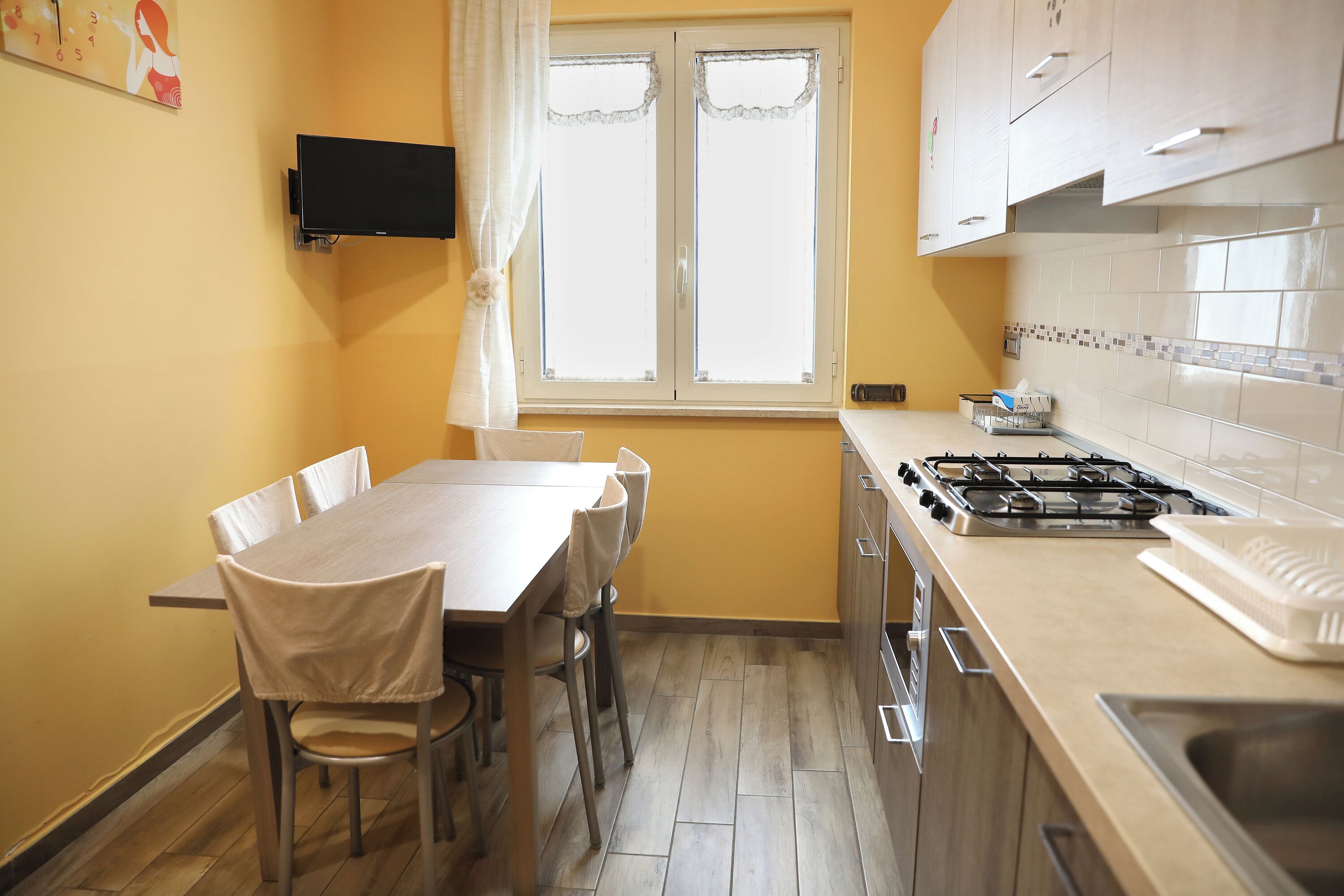 A kitchen with a dining table, chairs, a stove, and a sink.