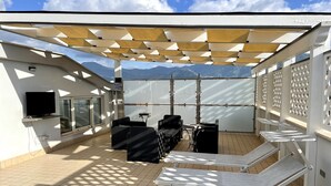 A rooftop terrace with a TV, seating, and a view of mountains. - Villa Magiola (Pompei)