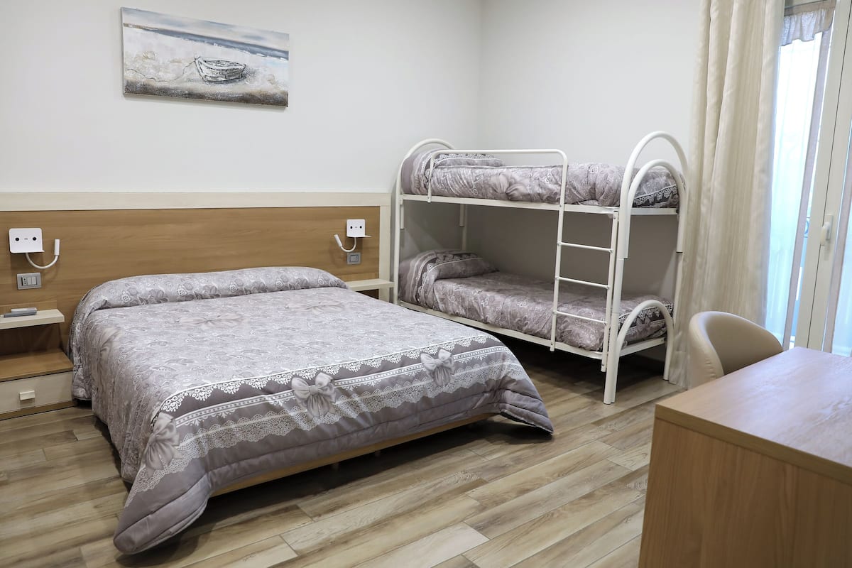 A room with a bunk bed, a desk, and a chair.