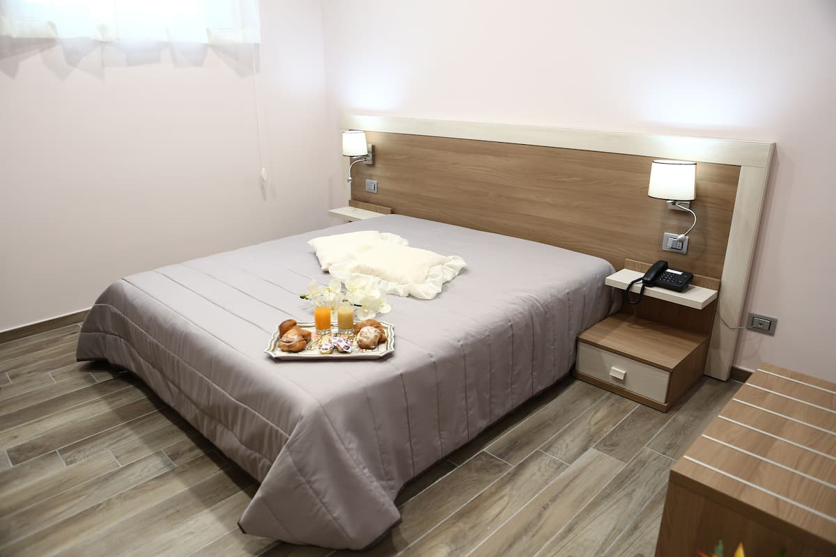 A neatly made bed with a tray of breakfast items, a bedside table with a lamp, and a phone.
