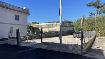 Un espace de stationnement clos, doté d’une barrière en béton, d’une clôture métallique et d’un lampadaire.