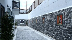 A cobblestone alleyway with stone walls, potted plants, and a sign for "MAGICIA." - Villa Magiola (Pompei)