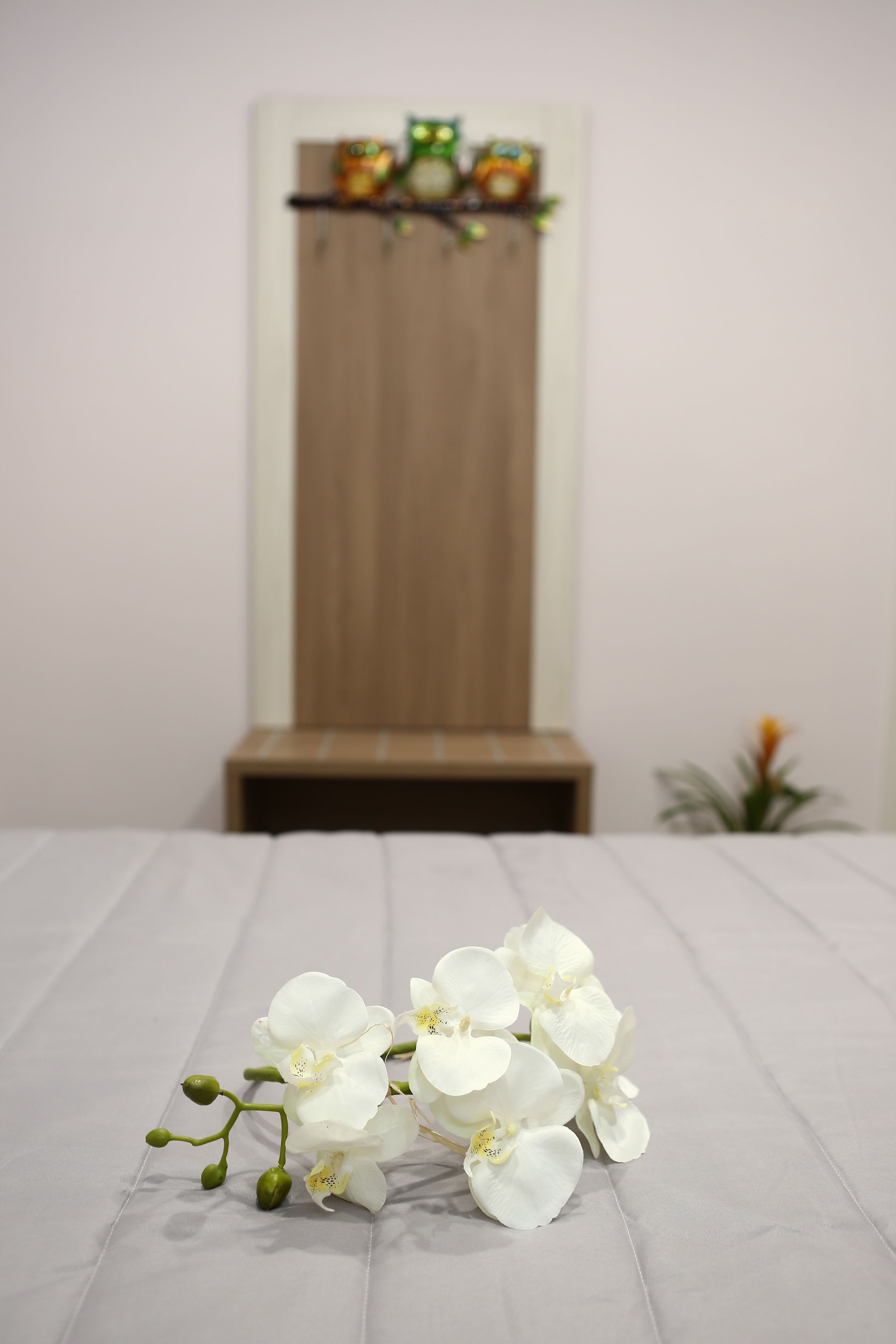 A bed with white sheets and a bouquet of white orchids on it.