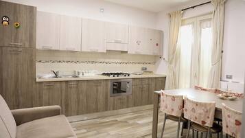A modern kitchen with wooden cabinets, a built-in oven, and a dining area with a table and chairs.