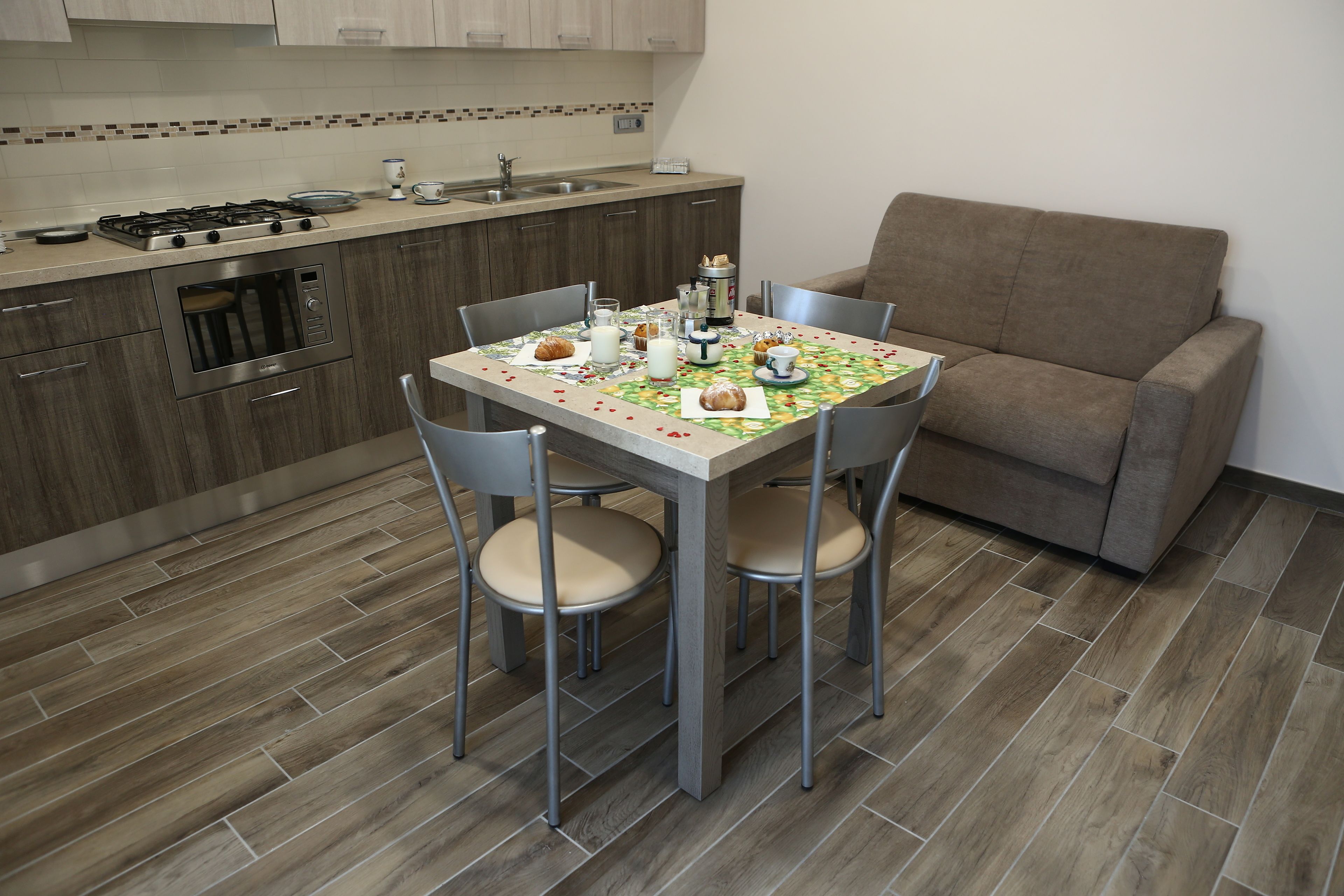 A kitchen with a dining table, chairs, and a sofa.