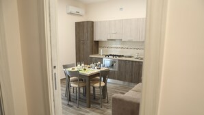 A compact kitchen with a dining table and chairs, a microwave, and a stove. - Villa Magiola (Pompei)
