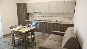 A compact kitchen with a dining table, chairs, and a sofa. - Villa Magiola (Pompei)