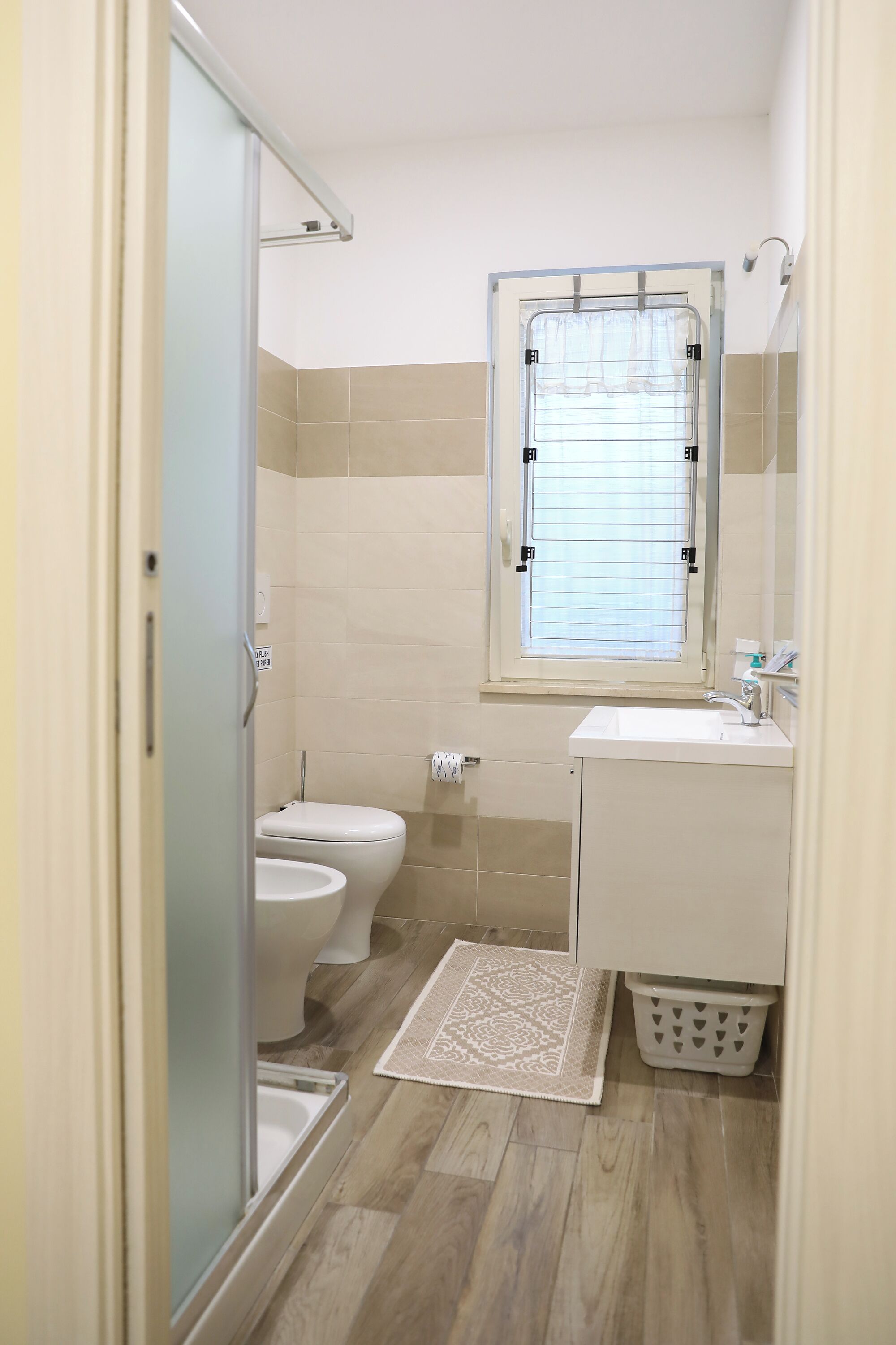 A small bathroom with a toilet, sink, and window.