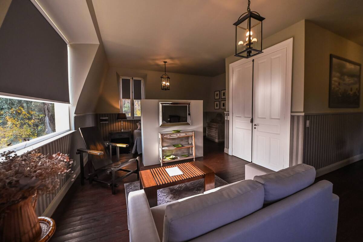 Um espaço de estar moderno estilo loft, com área de jantar, sofá, mesa de centro e televisão.
